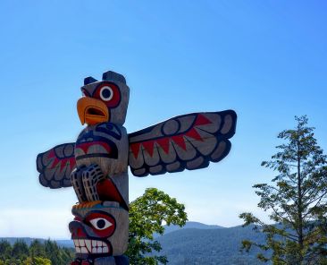 Cowichan Valley, Vancouver Island, Canada - June 18, 2018:. Native Americans totem on a background of the sea bay surrounded by mountains and coniferous forest.coniferous forest. Cowichan Valley, Vancouver Island, Canada