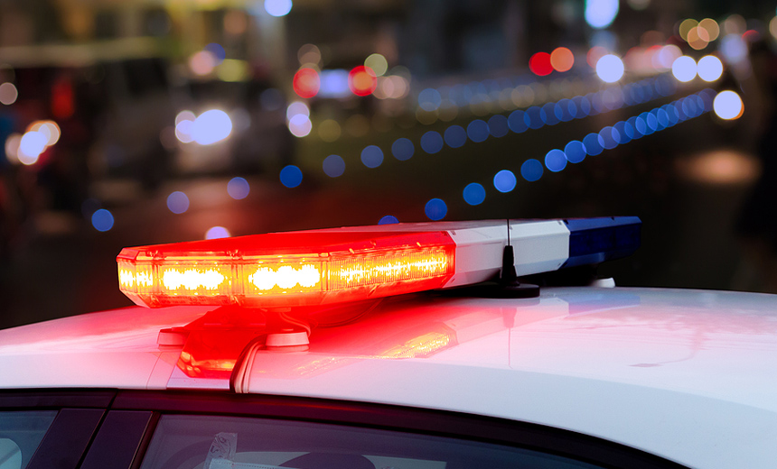 Red Flashing Sirens On Top Of Police Car Against Blurred Urban B