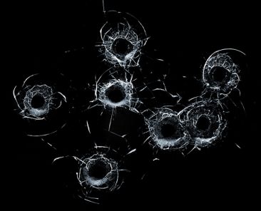 Broken glass multiple bullet holes in glass isolated on black background