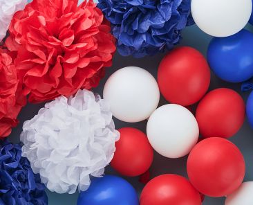 4th of July background. USA paper fans, Red, blue, white stars, balloons and gold confetti on blue wall background. Happy Labor Day, Independence Day, Presidents Day. American flag colors. Top view.