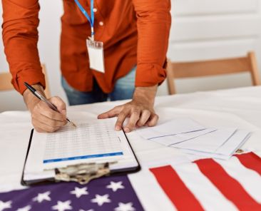 Young hispanic man writing on checklist at electoral college