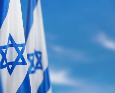 Israel flag with a star of David over cloudy sky background. Patriotic concept about Israel with national state symbols. Banner with place for text.