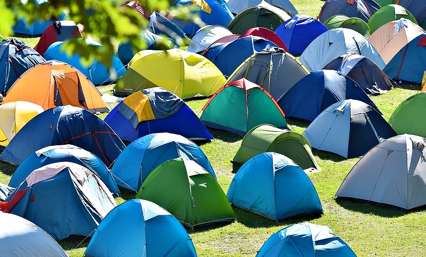 Lots of colorful tents on a meadow in a summer day during music festival