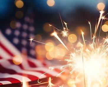 Sparkles with lights in soft focus and American flag on the background. July forth celebration. The Independence day backdrop. Abstract minimalistic wallpaper with space for text.