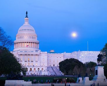 Washington, DC, USA - April 18, 2019: Capitol Building, at dusk with moon rise in background is the home of the United States Congress and the seat of the legislative branch of the U.S.